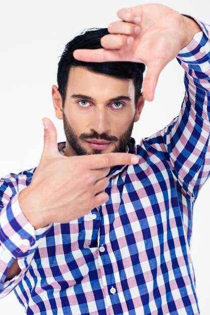 Portrait of a handsome man showing frame with fingers and looking at front isolated on a white wall