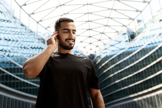 Portrait of handsome man wearing headphones walking at street