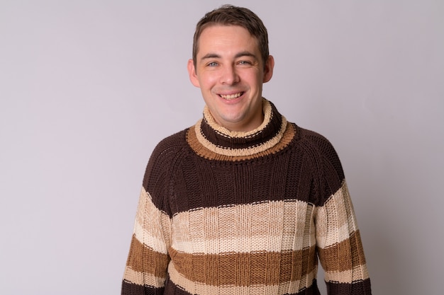 Portrait of handsome man wearing turtleneck sweater against white wall