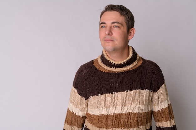 Portrait of handsome man wearing turtleneck sweater against white wall