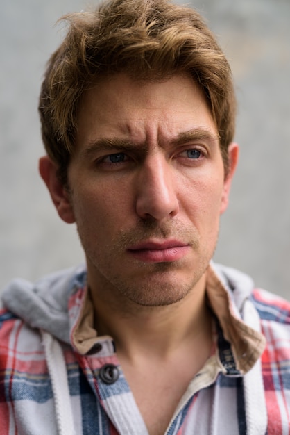 Portrait of handsome man with blond hair on concrete wall in the streets outdoors