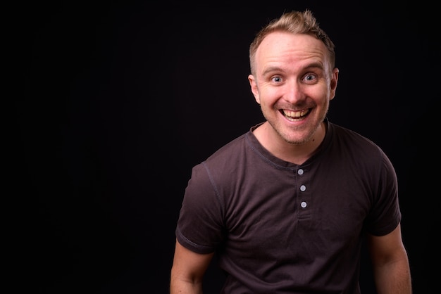 Portrait of handsome man with blonde hair against black wall