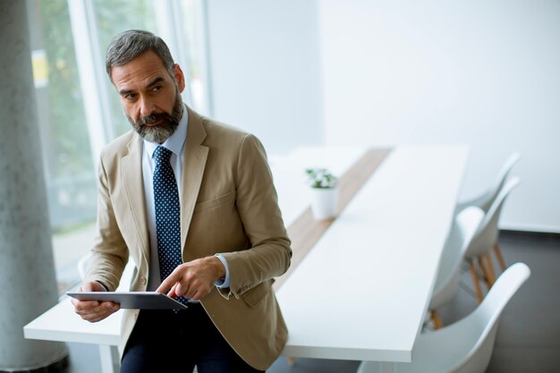 Portrait of handsome mature businessman with digital tablet in the office