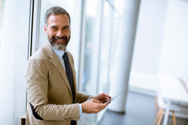 Portrait of handsome mature businessman with digital tablet in the office