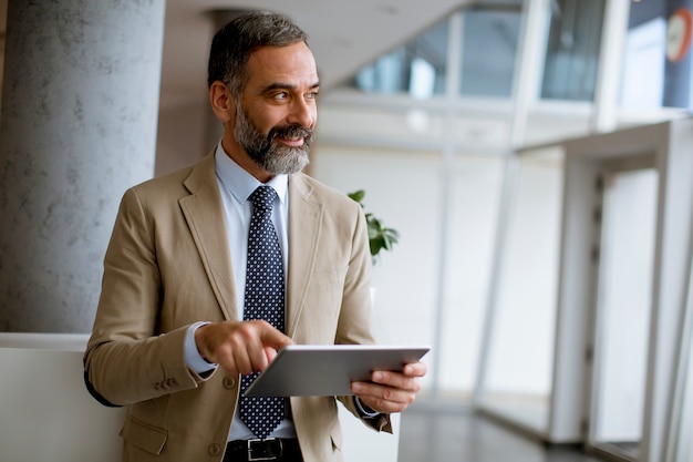 Portrait of handsome mature businessman with digital tablet in the office