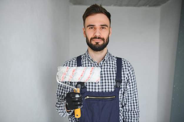 Portrait of handsome mechanic with stubble in blue overall shirt having his arms crossed looking at camera