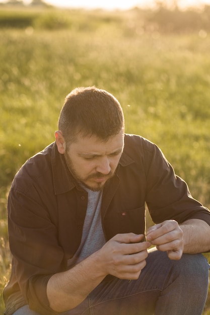 Portrait of handsome mid-adult man looking on hand , posing on summer meadow, image toned.