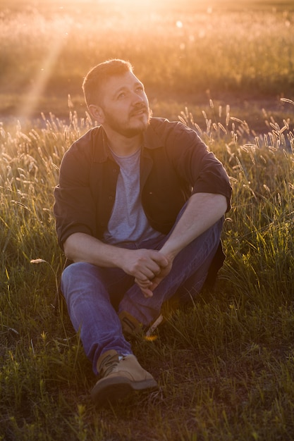 Portrait of handsome mid-adult man posing on summer meadow, image toned.