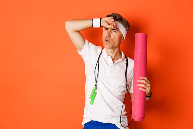 Portrait of handsome middle aged man, tired after fitness exercises