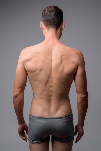 portrait of handsome muscular shirtless man on gray