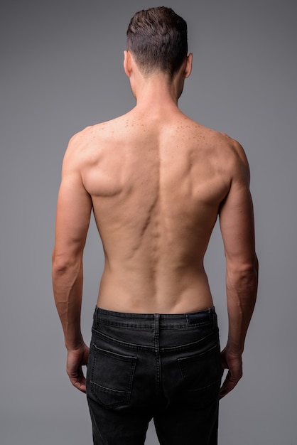 portrait of handsome muscular shirtless man on gray