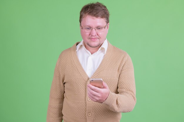Portrait of handsome overweight bearded man with eyeglasses against chroma key or green wall