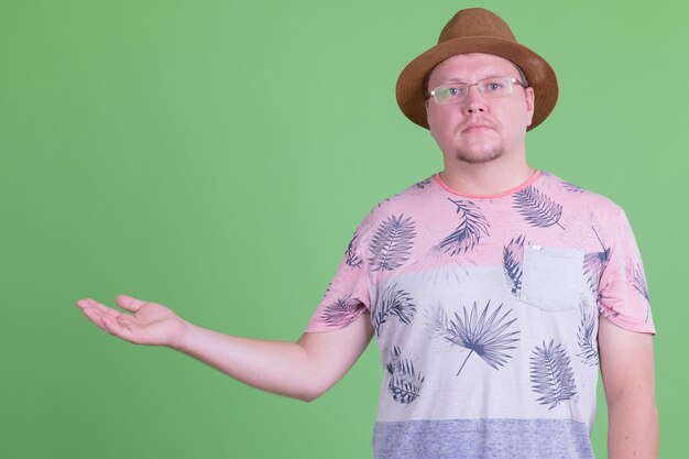 Photo portrait of handsome overweight bearded tourist man against chroma key or green wall