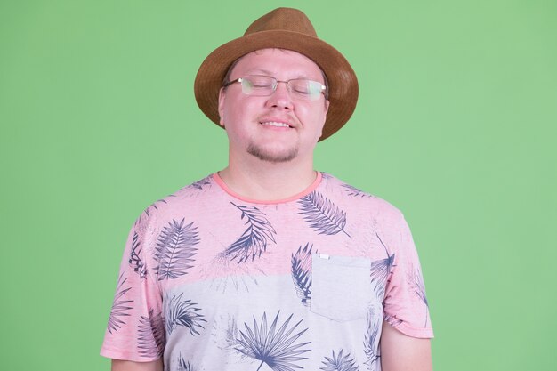 Portrait of handsome overweight bearded tourist man against chroma key or green wall