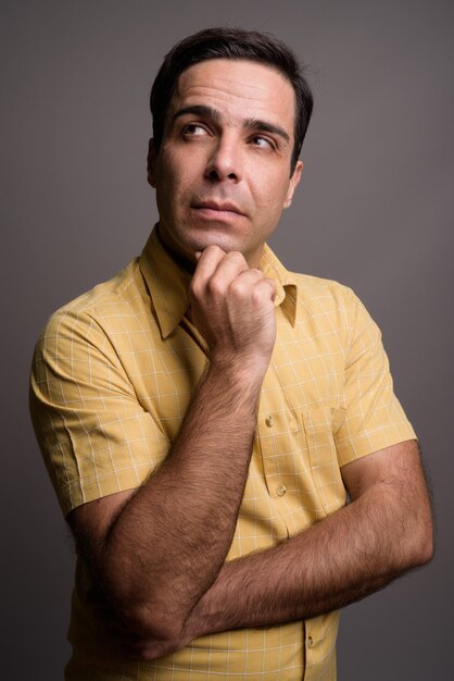 Portrait of handsome Persian man against gray wall