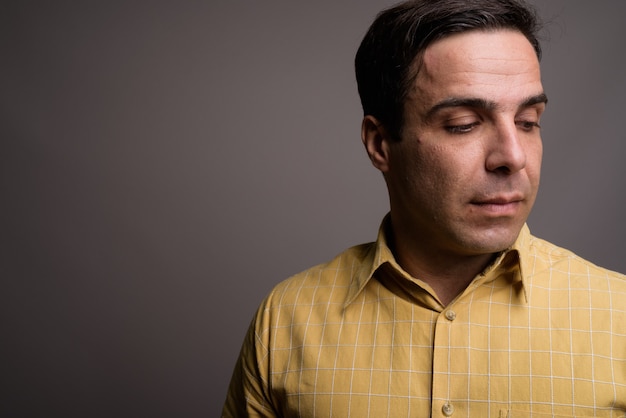 Portrait of handsome Persian man against gray wall