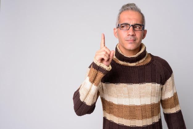 Portrait of handsome Persian man thinking and pointing up ready for winter