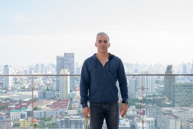 Portrait of handsome Persian man with gray hair against view of the city