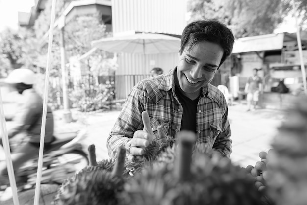 Portrait of handsome Persian tourist man spending holiday and exploring the city of Bangkok in black and white
