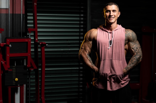 Portrait Of Handsome Personal Trainer Wearing Sportswear In Fitness Center Gym Standing Strong