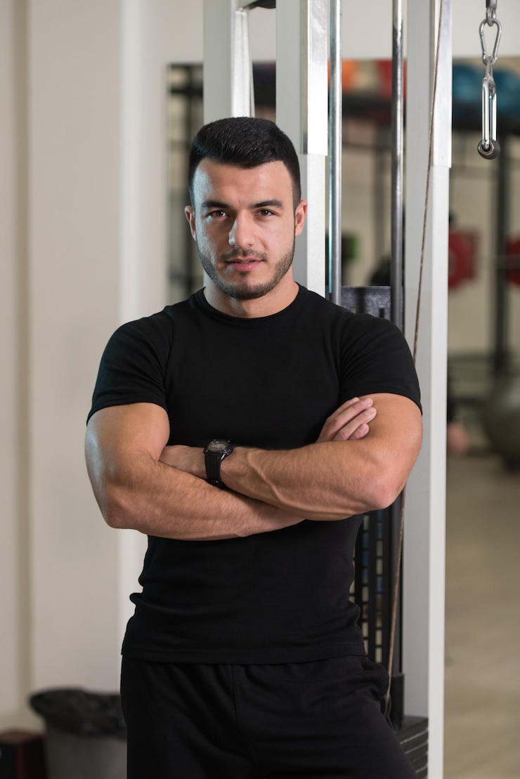 Photo portrait of handsome personal trainer wearing sportswear in fitness center gym standing strong