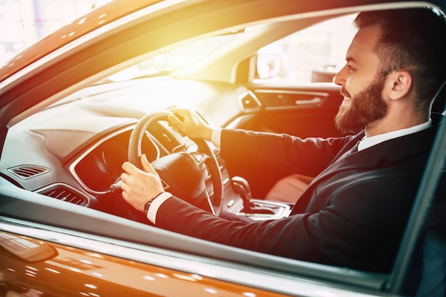 Portrait of an handsome positive smiling business man driving his car