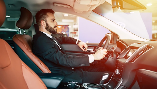 Portrait of an handsome positive smiling business man driving his car