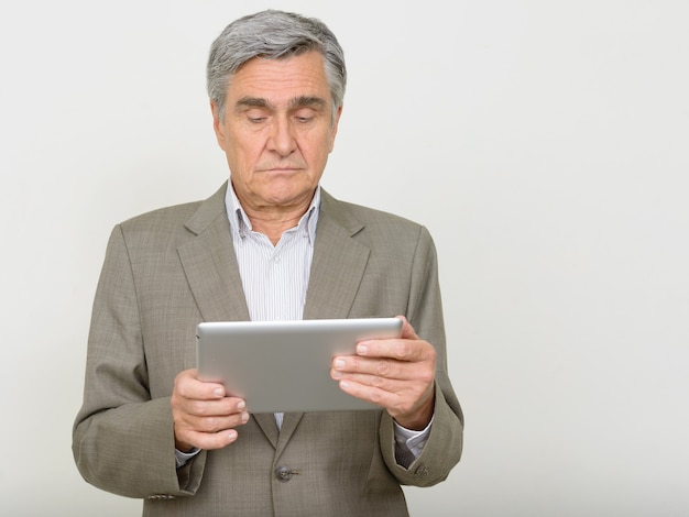 Portrait of handsome senior businessman using digital tablet