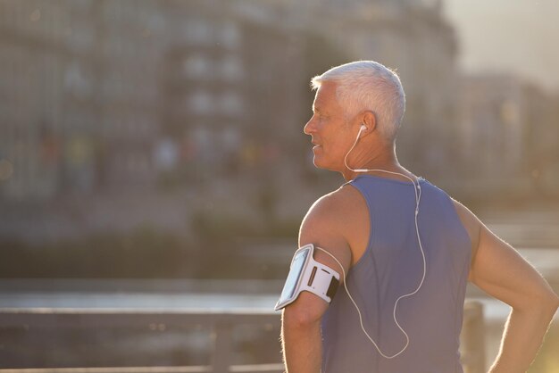 portrait of handsome senior jogging man while relaxing  and take break after morning run