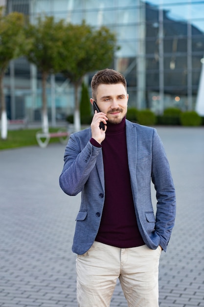 Portrait of handsome serious man in casual wear holding smartphone