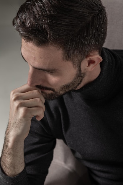 Portrait of a handsome and serious man leaning on his hand in thinking pose