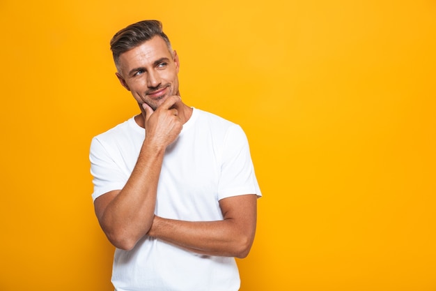 Portrait of a handsome serious man posing isolated on yellow wall.