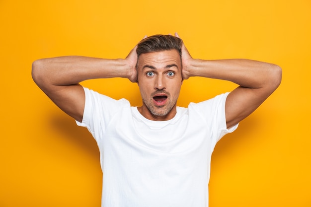 Portrait of a handsome shocked excited man posing isolated on yellow wall.