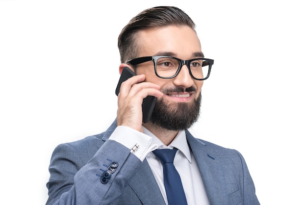 Portrait of handsome smiling businessman in grey suit using smartphone isolated on white