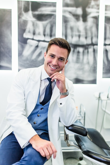 Portrait of handsome smiling dentist posing in his stomatology office.