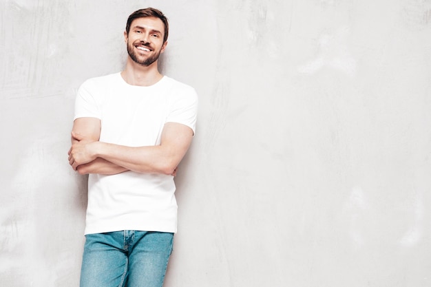 잘 생긴 웃는 세련된 힙스터 램버섹슈얼 모델의 초상화 T셔츠와 청바지를 입은 섹시한 남자 패션 남성 스튜디오에서 파란색 벽에 격리
