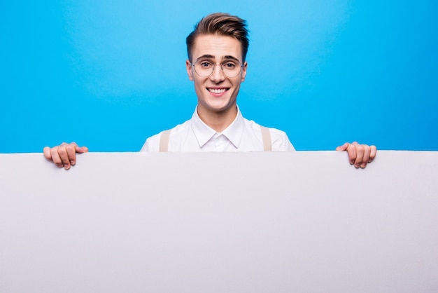 Portrait of handsome student posing against the blue wall