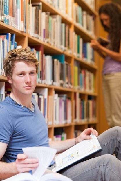 Portrait of a handsome student posing with a book while his clas