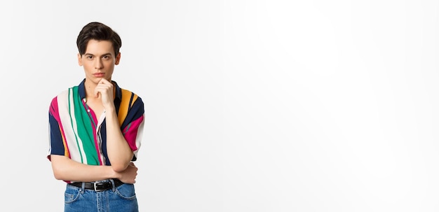 Photo portrait of handsome and stylish man looking thoughtful at camera making choice thinking at staring at you standing over white background