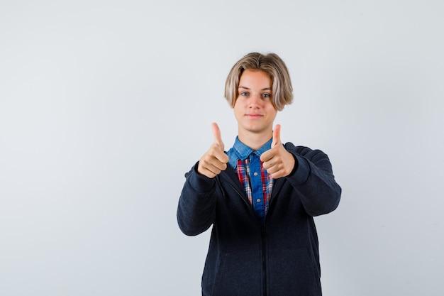 Portrait of handsome teen boy showing double thumbs up in shirt, hoodie and looking jolly front view