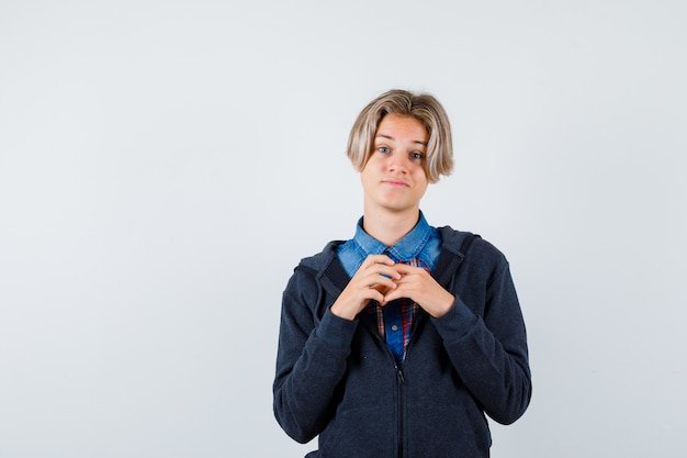 Portrait of handsome teen boy with hands over chest in shirt, hoodie and looking hopeful front view