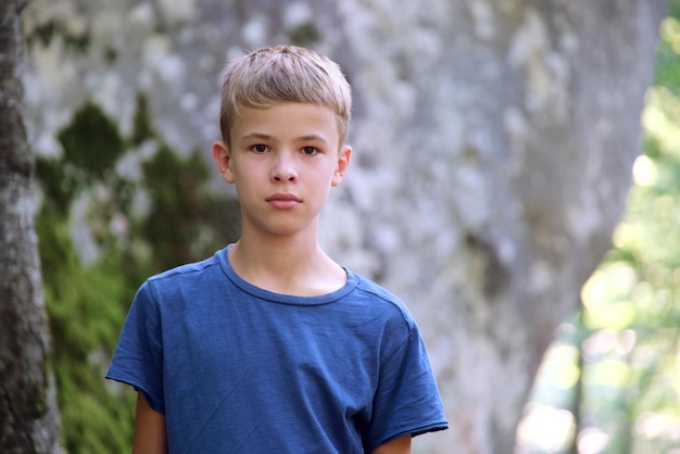 Photo portrait of handsome teenager boy in casual clothes smiling in camera on green sunny background