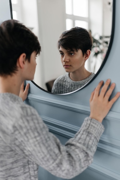 Photo portrait of a handsome teenager standing near the wall indoors