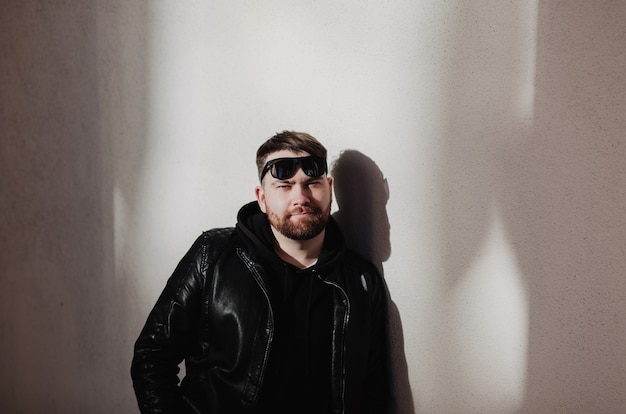 Portrait of handsome trendy man in black leather jacket and sunglasses