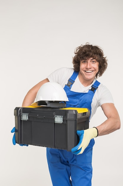 Portrait of handsome white male builder laughing on white wall.