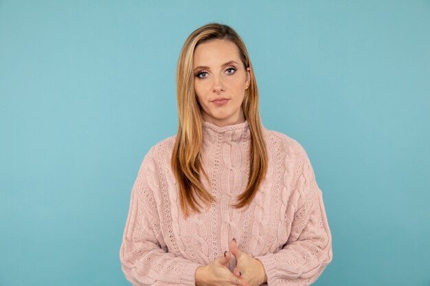 Portrait of handsome woman in the sweater posing on the blue background.