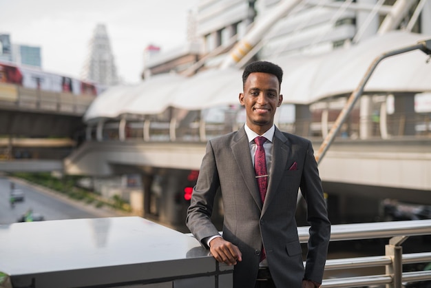 Portrait of handsome young African businessman outdoors in city