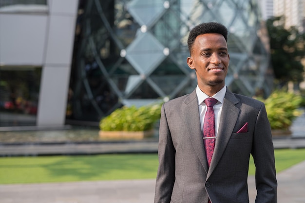 Portrait of handsome young African businessman outdoors in city