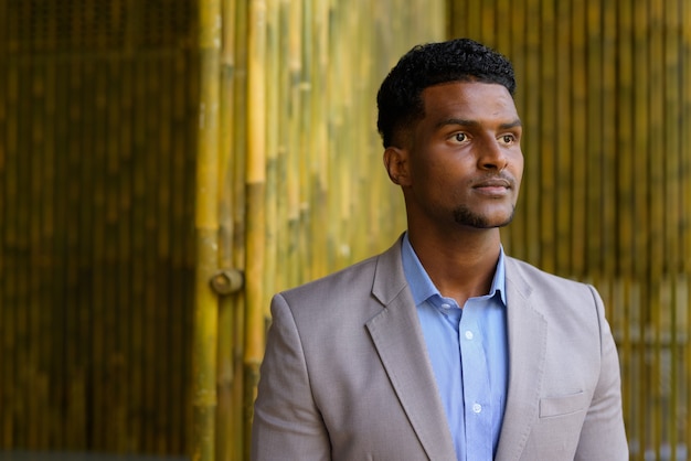 Portrait of handsome young African businessman thinking outdoors