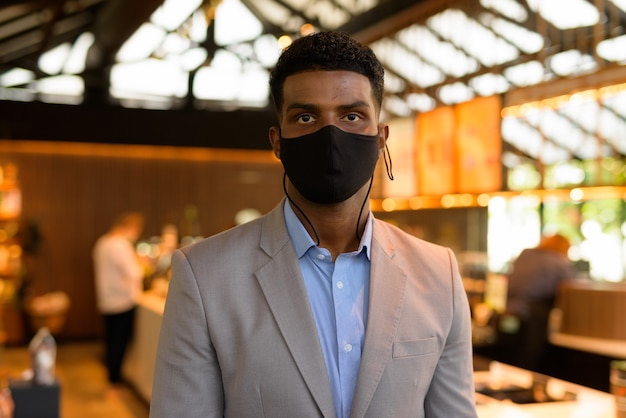 Portrait of handsome young African businessman wearing suit and face mask